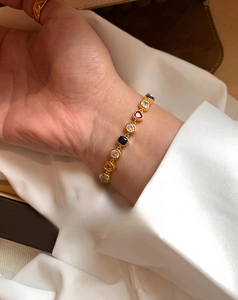 Gros plan d'un bracelet plaqué or 18 carats avec zircons colorés en cœur et perles au poignet