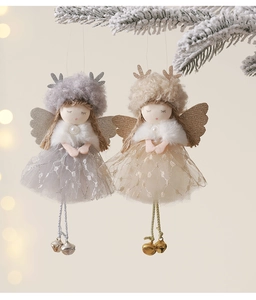 Detail of plush Christmas angel dolls with tulle skirts hanging on snowy pine branches