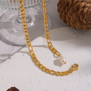 18K gold Figaro chain necklace with a natural freshwater pearl pendant on a stone base