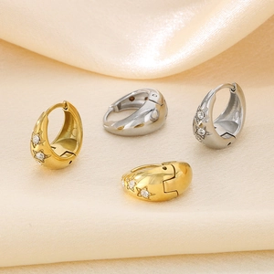 Close-up of gold and silver U-shaped hoop earrings with star engraving and cubic zirconia