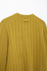 Close-up of mustard yellow cable knit cardigan showing texture and round neck detail
