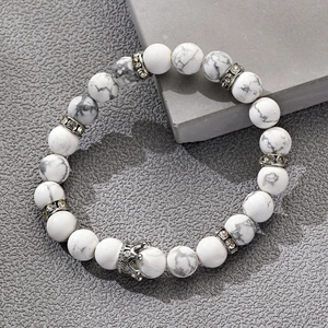 Perlenarmband aus weißem Türkis 8mm mit silbernem Kronenanhänger auf grauem Hintergrund