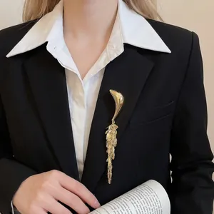 Elegant gold fringe brooch with metal leaf tassels on a black suit lapel for women