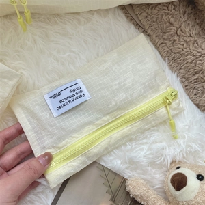 Close-up of a small light yellow checkered travel organizer bag with a sturdy zipper