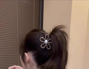 Close-up of sparkling sunflower hair claw with central pearl and rhinestone detailing
