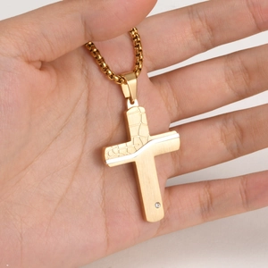 Detail of a gold cracked cross pendant necklace featuring a small inset gemstone
