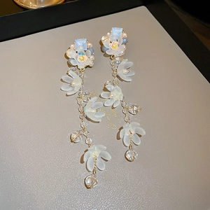 Detailed shot of long tassel earrings with white matte flowers and light blue gemstones