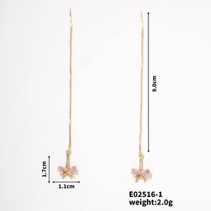 Detailed view of long gold Eiffel Tower drop earrings with pink bow accents and size labels