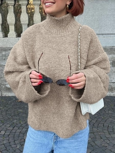Détail d'un pull à col roulé kaki clair avec texture en maille et coupe décontractée
