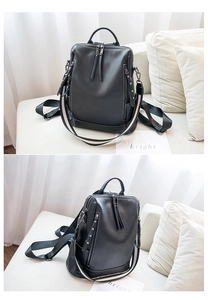 Detail view of black leather backpack with metal rivets and striped shoulder straps