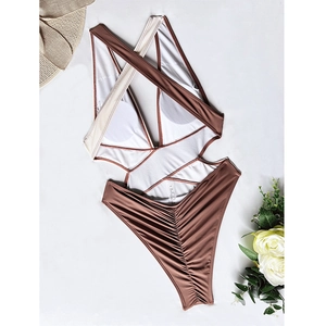 Detailed flat lay of crossover one-piece swimsuit with ruching and contrast tones
