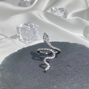 Macro shot of silver snake ring with crystals on black stone and white silk background