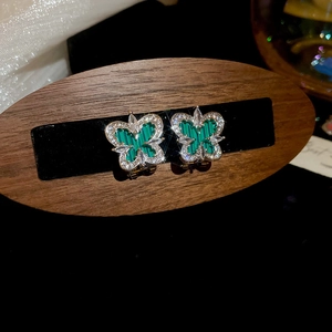 Macro shot of gold butterfly earrings with green malachite texture and zircon inlay