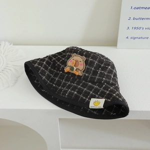 Détail du chapeau bob à carreaux marron pour enfant avec écusson dessin animé Capybara