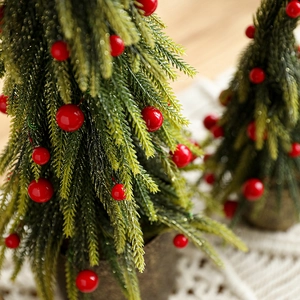 Mini green Christmas tree with red berries and gold glitter in a wrapped pot base