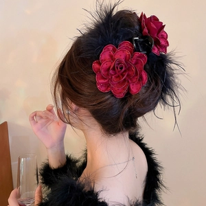 Detail of burgundy fabric roses and black feathers on a large claw hair clip for women