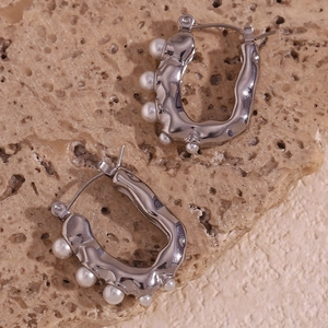 Macro detail of silver U-shaped lava texture earrings with pearls on stone