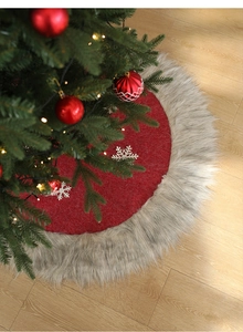 Detail of red Christmas tree skirt with plush grey trim and white snowflake patterns