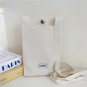 Detail of cream knitted phone bag with silver snap button and minimalist logo tag