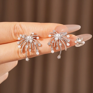 Close-up of starburst pearl earrings with sparkling cubic zirconia on silver pins