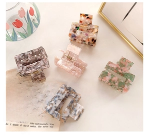 Flat lay of five acetate floral and marble pattern hair claw clips for women styling