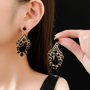 Close-up of vintage gold earrings with large black teardrop stones worn by a model