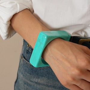Close-up of a wide square acrylic bangle with blue marble texture on a model's wrist