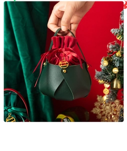 Christmas gift bag with red velvet and green PU leather held by a hand in festive setting