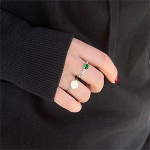 Close-up of 925 sterling silver rings set with a green emerald gemstone on a hand