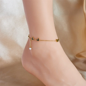 Elegant gold butterfly anklet with black pendants and a white pearl on satin background