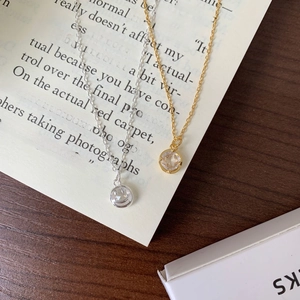 Detail of round zircon pendant on gold and silver chains over vintage book page