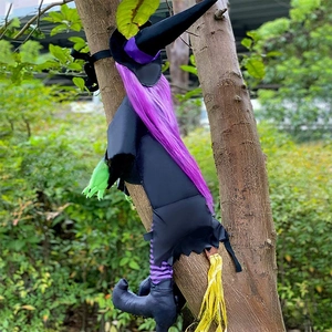 Outdoor Halloween crashing witch decoration with purple hair and broom on a tree trunk
