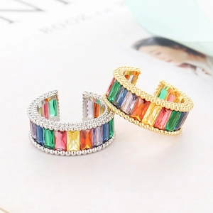 Macro detail of gold and silver rings with rainbow baguette gemstones and beaded edges