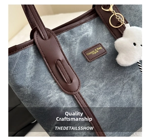 Macro view of vintage denim tote bag with leather trim and plush cloud pendant detail