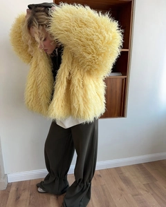 Detail shot of bright yellow oversized faux fur coat showing its long fluffy texture