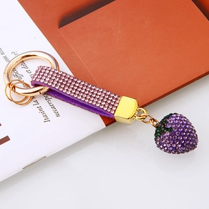 Macro detail of purple strawberry keychain with sparkling rhinestones and gold-tone metal