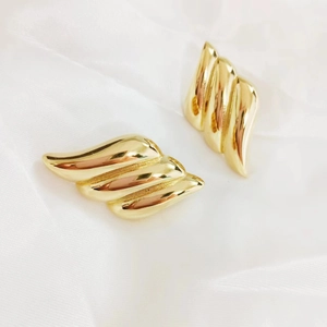 Detailed view of 18K gold plated geometric wing earrings with polished wavy texture