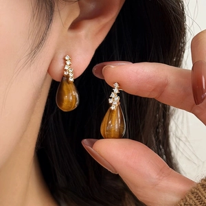 Tiger eye teardrop earrings with zircons and gold-plated finish on model