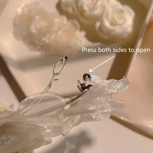 Elegant white camellia hair clip with layered mesh petals and a metal spring clamp