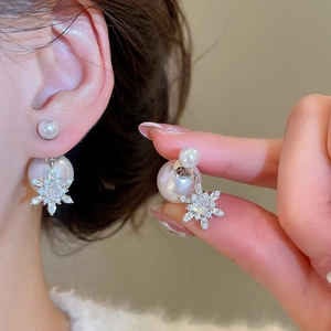 Makroaufnahme von Schneeflocken-Perlenohrringen mit Zirkonia an einem Modellohr