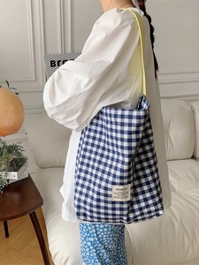 Blue and white gingham canvas tote bag with yellow shoulder strap shown on a model