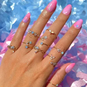 Macro shot of gold butterfly and moon rings with opal stones on a hand with soft background