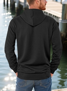 Rear view of black hooded sweatshirt with geometric embossed texture by the waterfront