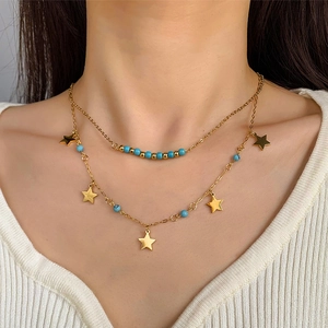 Détail du collier double rang en acier titane doré avec perles bleues et pendentifs étoiles