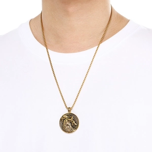Detailed view of a gold Celtic wolf pendant necklace worn by a model on a white tee