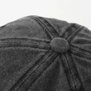 Macro detail of dark grey washed baseball cap showing stitching and top button texture
