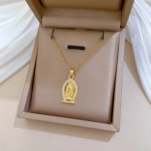 Close-up of a gold oval portrait pendant with sparkling crystals in a beige jewelry box