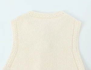 Détail du gilet en maille crème montrant le col rond et la texture du coton