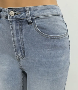 Macro-opname van een hoge taille jeans met metalen knoop en precieze stikseldetails