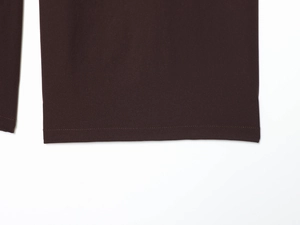 Detail of dark brown trousers showing the double-folded hem and woven fabric texture